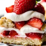 Close-up of a layered strawberry shortcake showcasing juicy strawberries and creamy whipped topping.