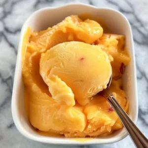Delicious homemade peach sorbet in a white dish, ready to be scooped.