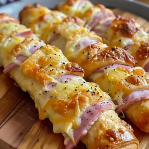 Close-up of several golden-brown ham and cheese sticks, baked to perfection and arranged on a white plate.