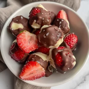 Close-up of chocolate-covered strawberry yogurt bites sprinkled with sea salt.