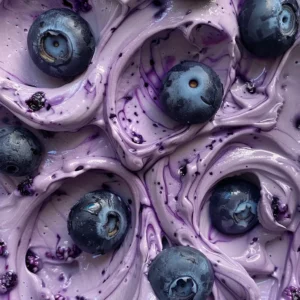 Close-up of several creamy white yogurt bites swirled with purple blueberry, arranged on a wooden plate with fresh blueberries.