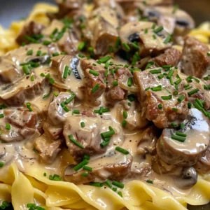 Close-up of creamy beef stroganoff in a skillet, garnished with fresh chives.